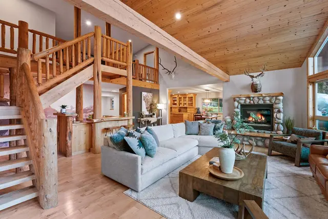 Gather your whole crew on the teal sectional beneath the antler-topped stone fireplace, loft staircase just behind.