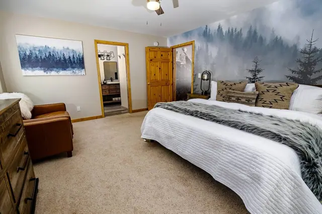 Sink into the king bed under a gray fur throw with the forest mural at your back and the ensuite bath just steps away.
