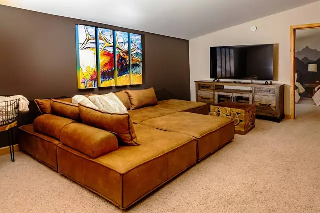 Claim the leather daybed sectional for your movie night under the four-panel elk artwork and mounted TV.