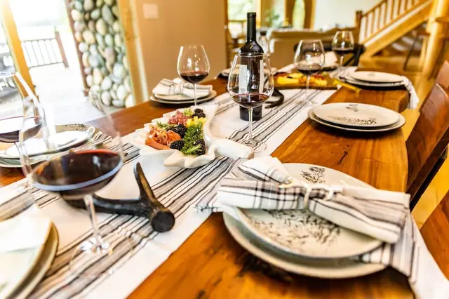Sit down to a table set with wine glasses and charcuterie, striped runner and folded napkins ready for you.
