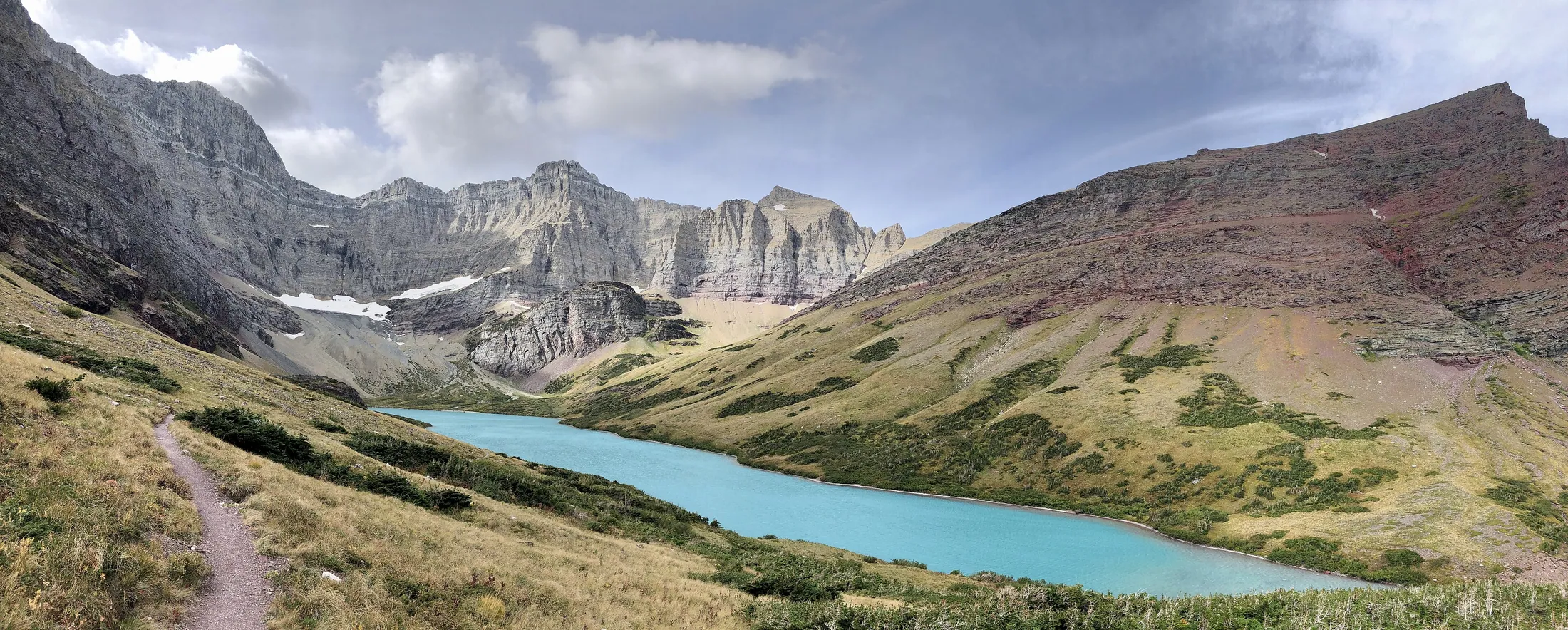 Cracker Lake, a turquoise glacial lake below grey cliffs in Glacier National Park