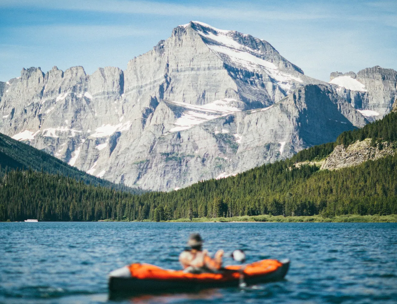 A kayaker crossing Swiftcurrent Lake below Mount Grinnell