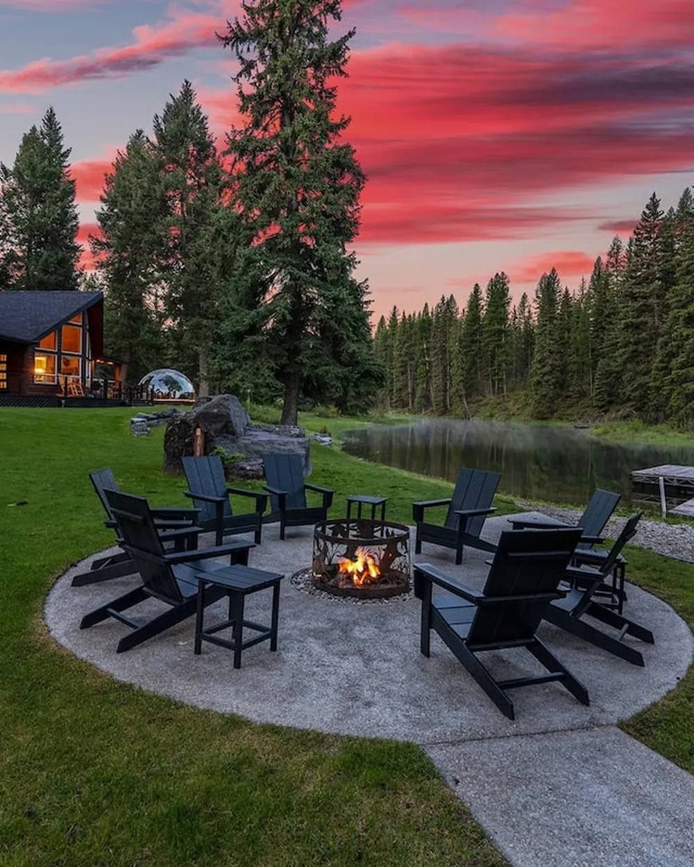 The fire pit at Lodge 93 lit at dusk, the barrel sauna and the dock waiting behind it