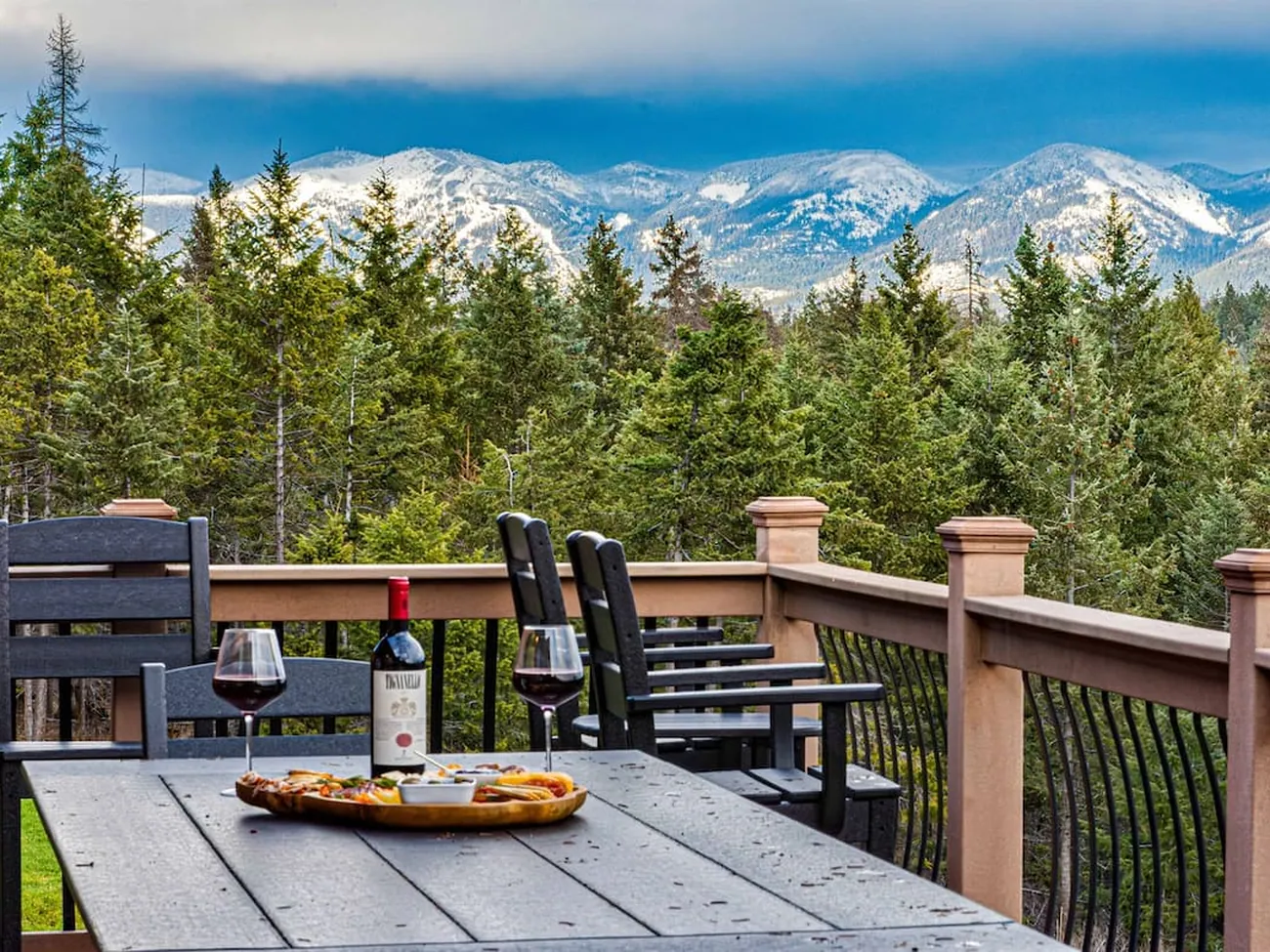 A long deck table laid with wine and charcuterie above the treetops