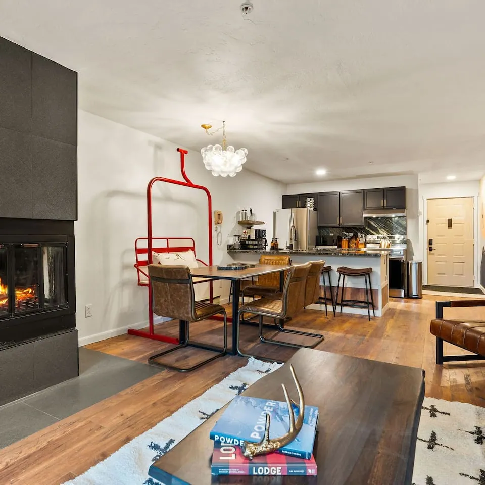 The dining table at Chasing Powder with its retired chairlift bench, the fireplace and living room beyond