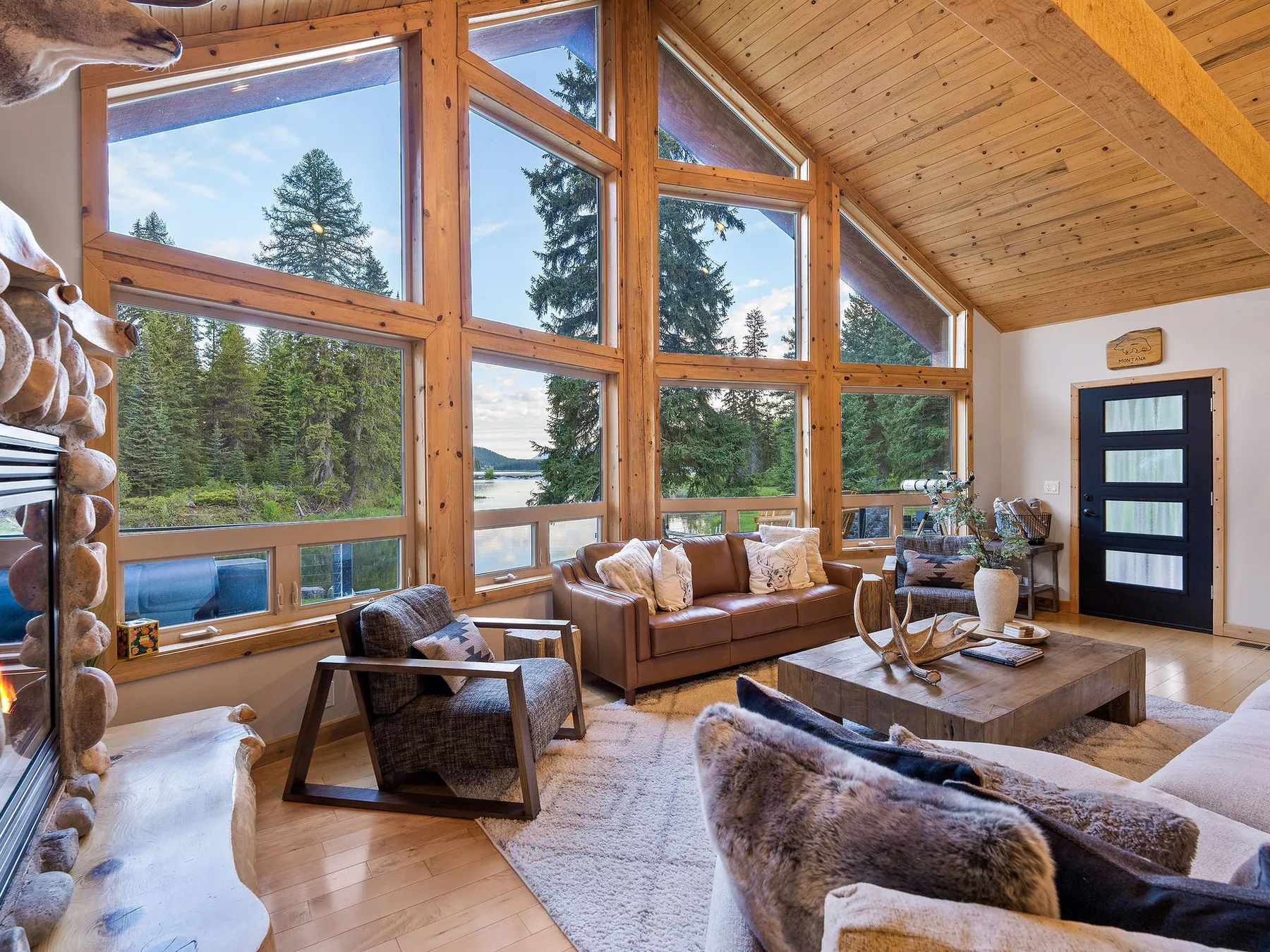 A vaulted living room photographed properly, forest through floor-to-ceiling glass