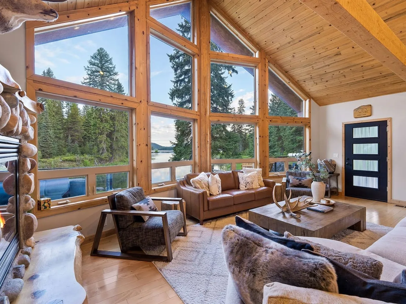 A vaulted living room photographed properly, forest through floor-to-ceiling glass