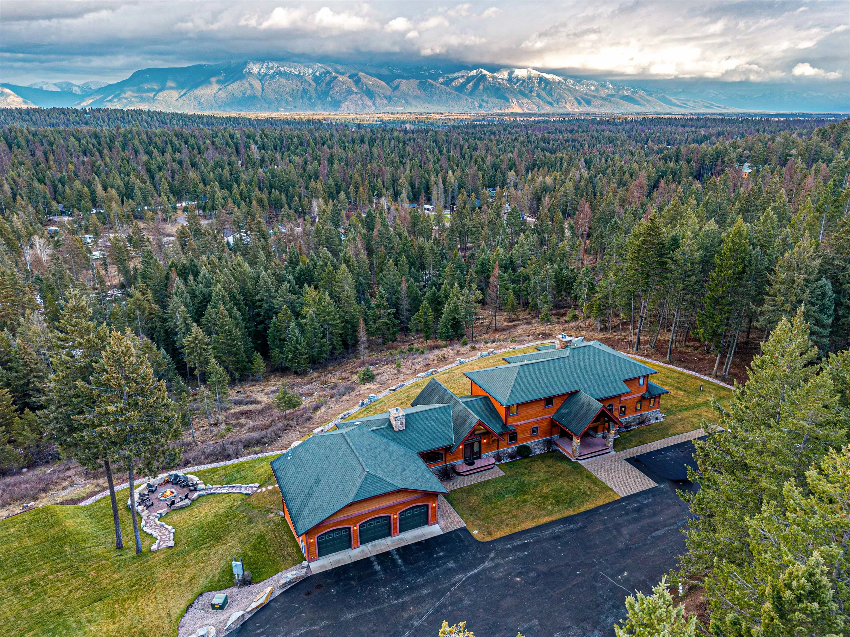 A lodge among the pines from the air, the Whitefish valley beyond it