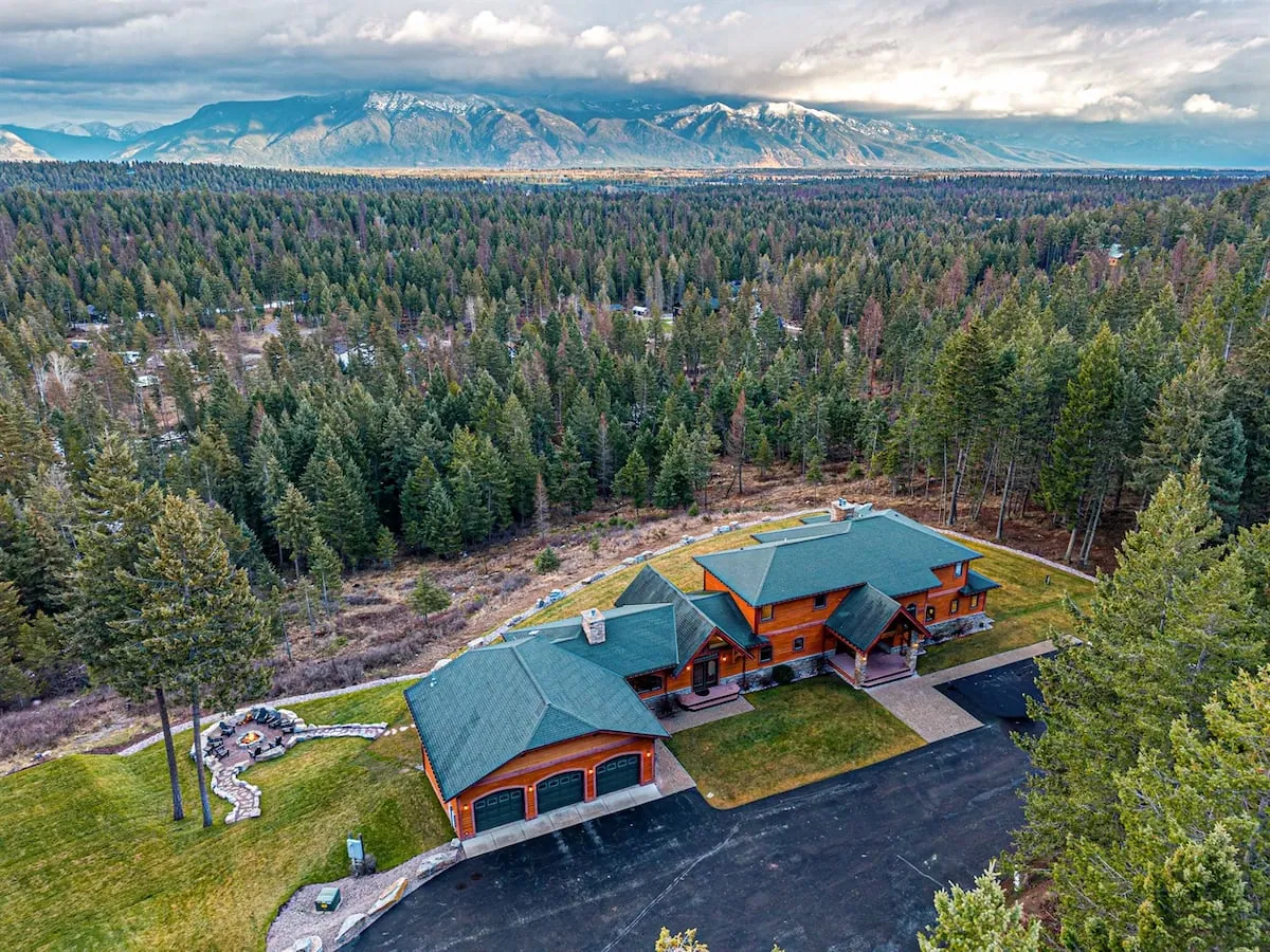 A lodge among the pines from the air, the Whitefish valley beyond it