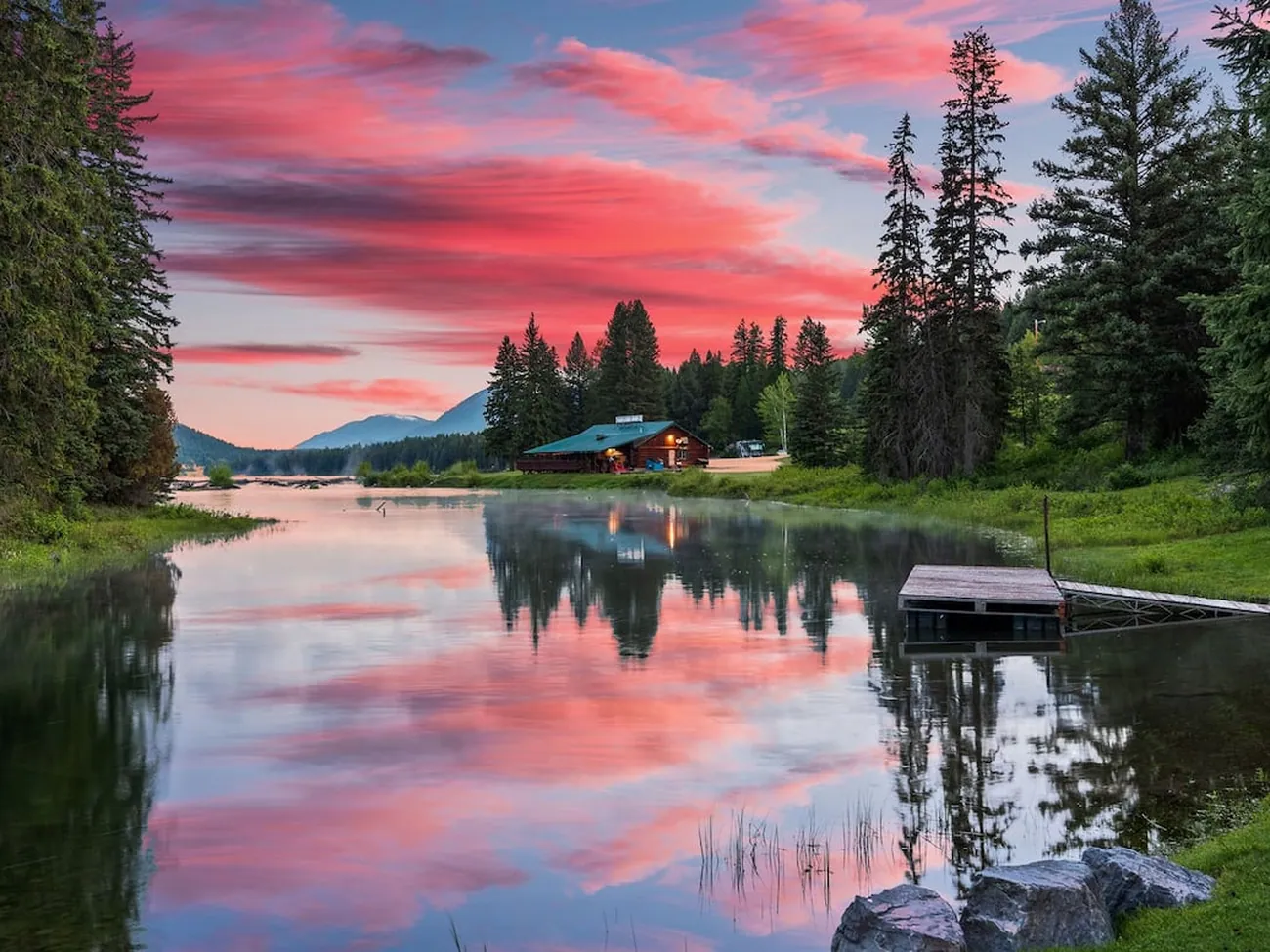 The Stillwater river channel at sunset, the dock and the cabin small among the pines