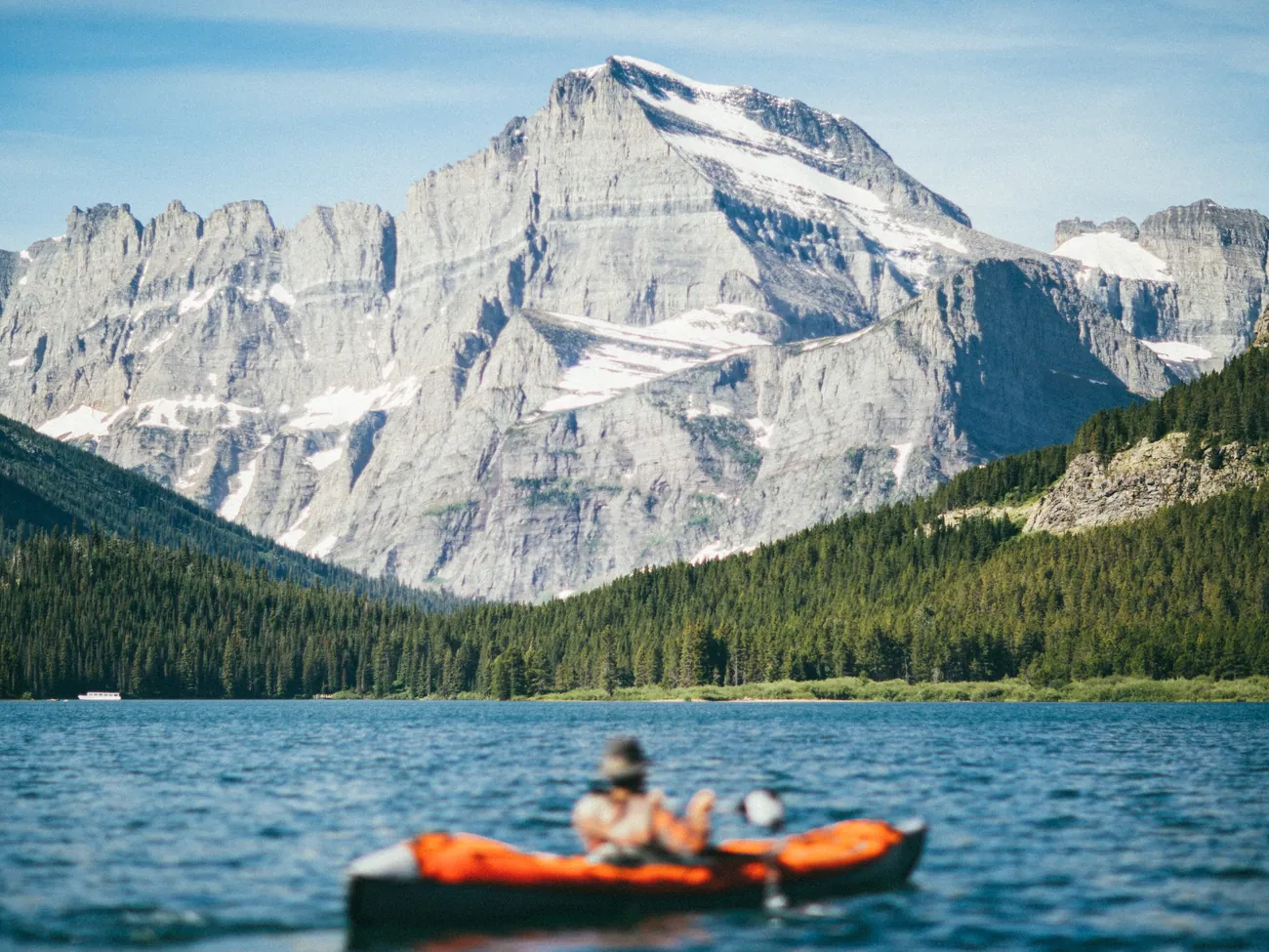A kayaker crossing Swiftcurrent Lake below Mount Grinnell