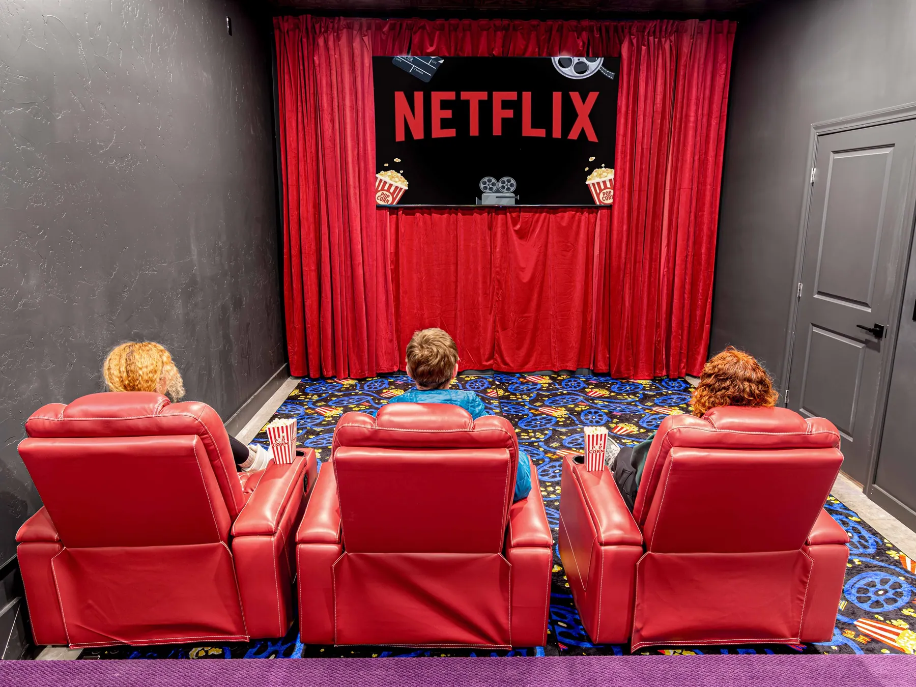 Three rows of red recliners facing the screen in the 12-seat theater