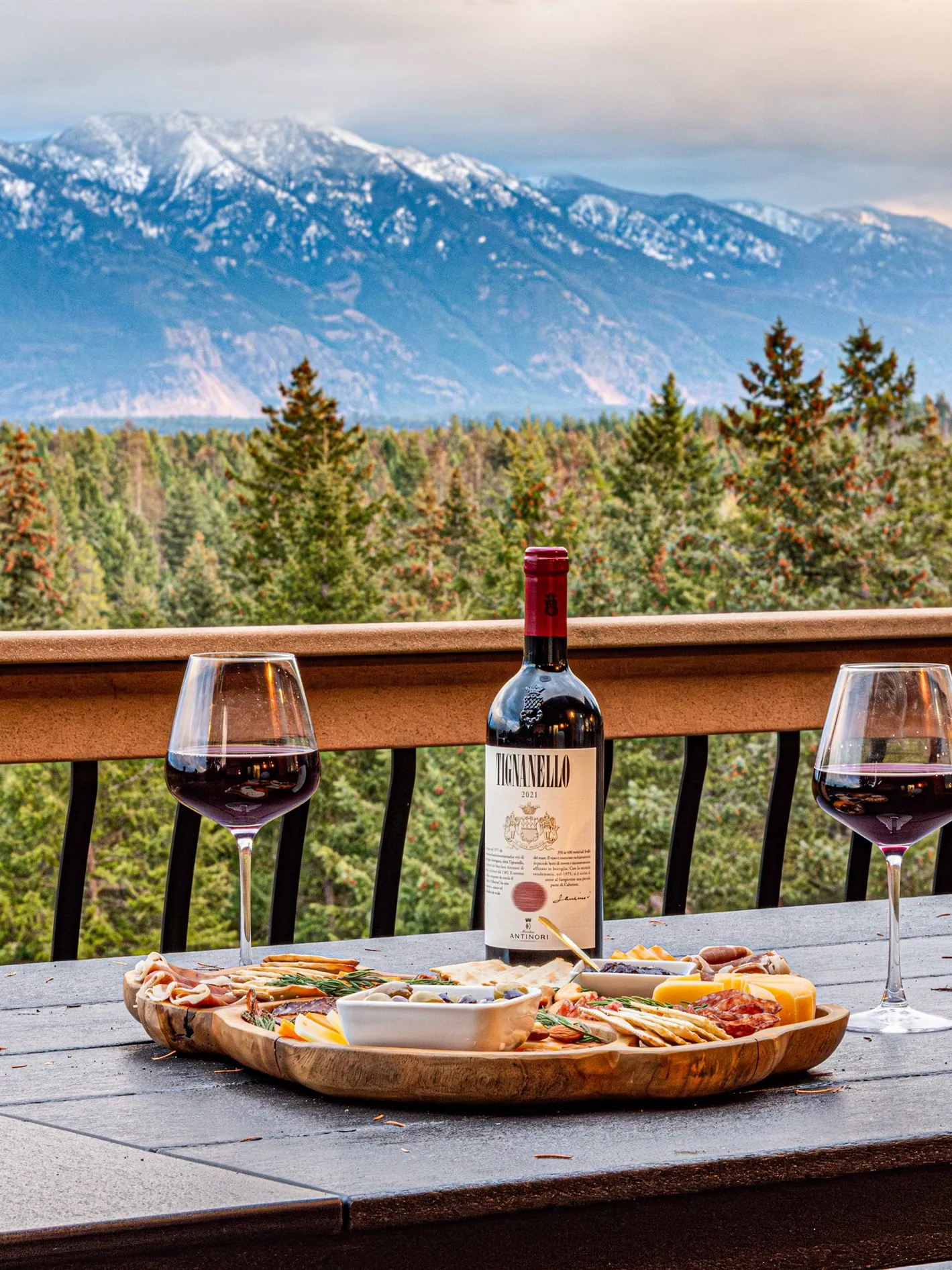 Wine poured and a board laid out on the deck rail with the snow-capped range beyond