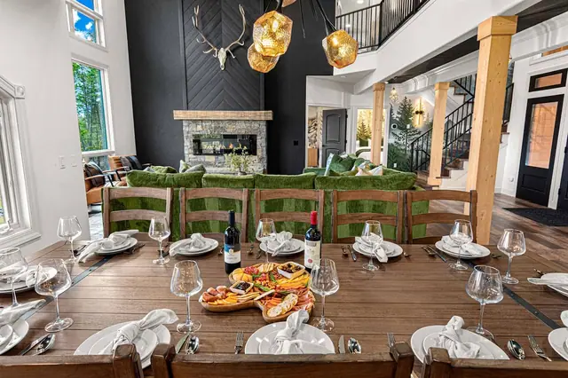 Set the long table for the whole crew, fireplace glowing and the staircase framing the room behind you.