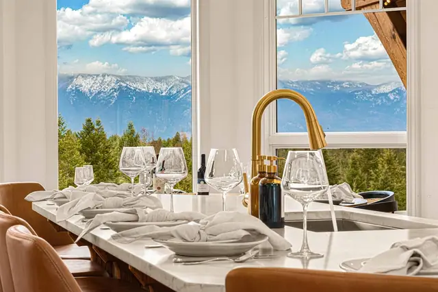 Pour the wine right by the kitchen sink while floor-to-ceiling windows frame the dramatic peaks behind the table.