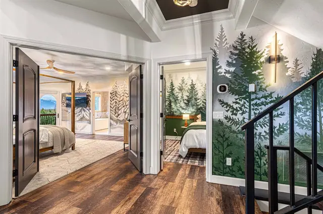 Push open the black double doors into the primary wing, with a staircase framed by a forest mural to your right.