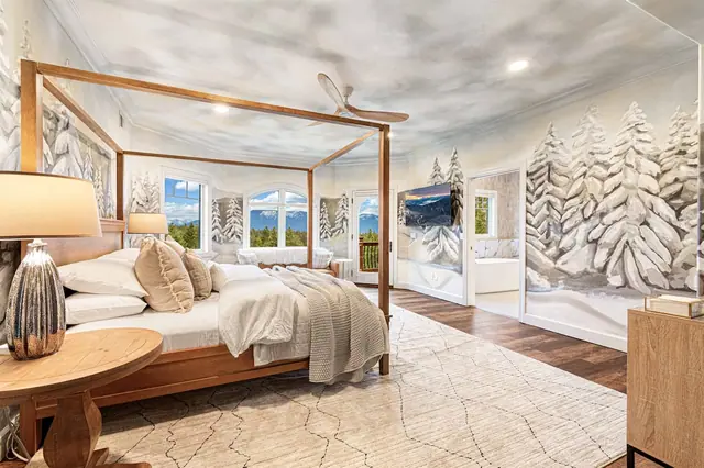 Climb into the canopy bed surrounded by a floor-to-ceiling snow-forest mural, with a walk-in dressing area just behind you.