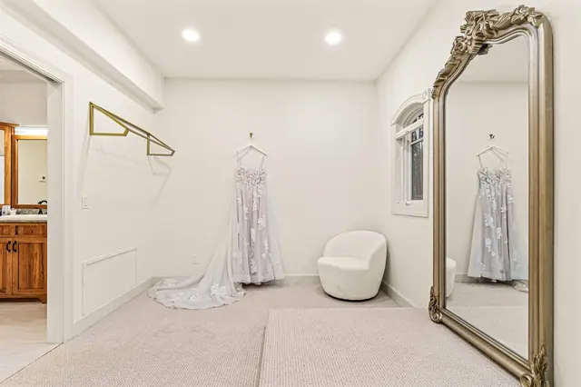 Catch your reflection in the ornate mirror as the dress hangs ready and the vanity waits just through the doorway.