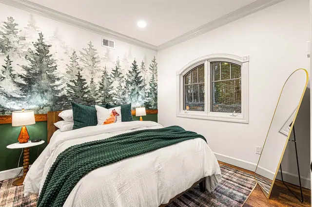 Settle into the Pine Room where a forest mural headboard and a hand-painted fox pillow set the woodland scene.