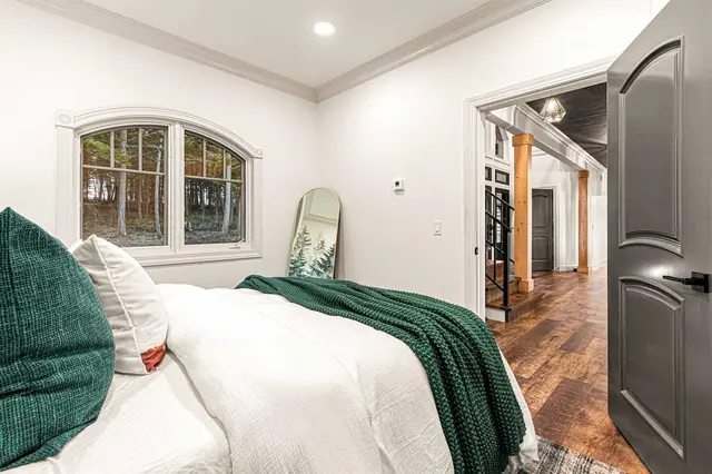 Wake to a forest view through your arched window in the Pine Room, mirror and hallway just past the open door.