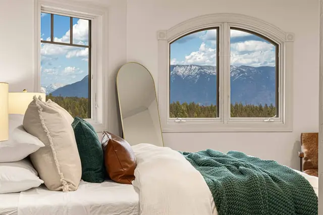 Pile the pillows against the headboard and catch your mountain view through the arched windows beside the bed.