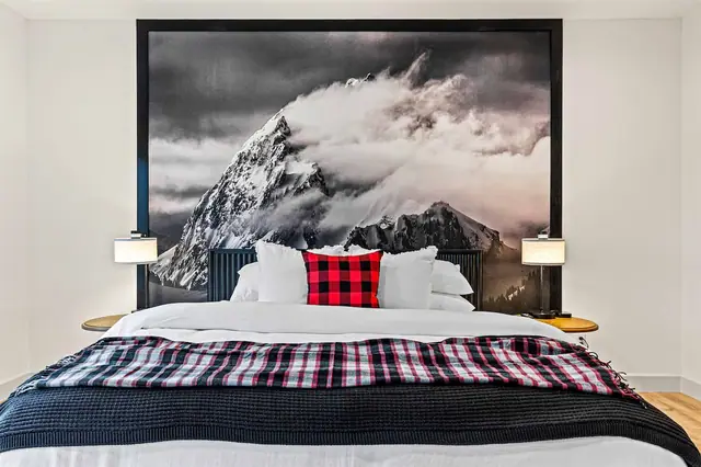 Fold back the plaid throw on the king bed with the black-and-white mountain photograph rising behind the headboard.