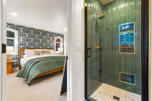 Rinse off in the glass shower just steps from the antler-wallpaper bedroom through the open doorway.