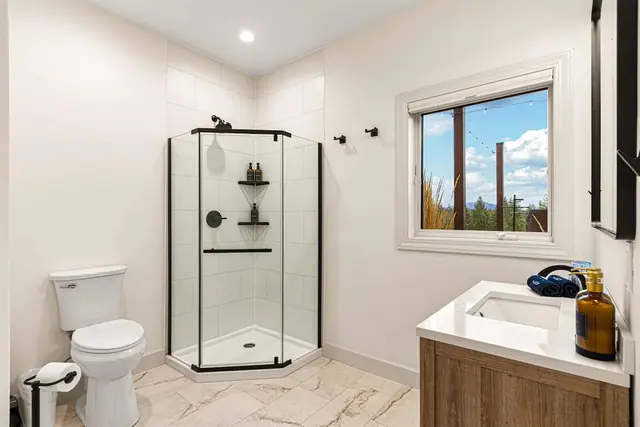 Rinse off in the corner shower with a forested mountain view through the window beside you.