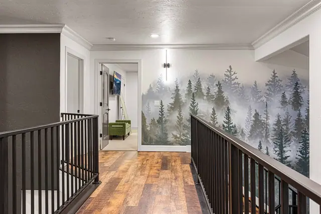 Wander the upstairs landing past the forest mural for a glimpse of the green-couch lounge beyond the railing.